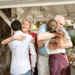 A joyful family reunion outdoors with warm hugs and smiles under a wooden pergola.